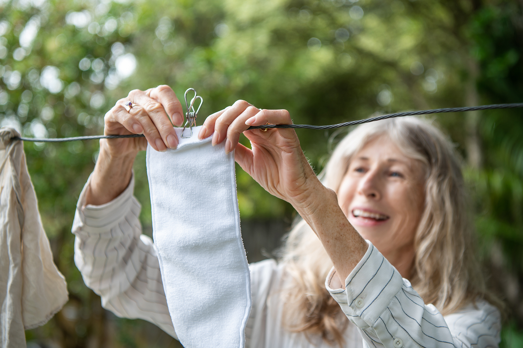 A woman hanging up laundry with stainless steel pegs from Cali Woods in Wanaka.