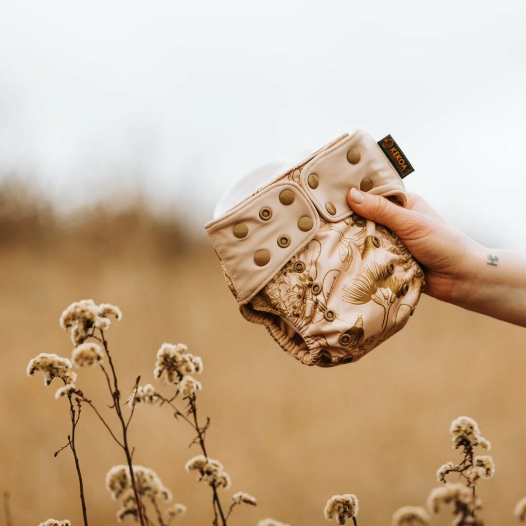 A reusable nappy being held up in a field.