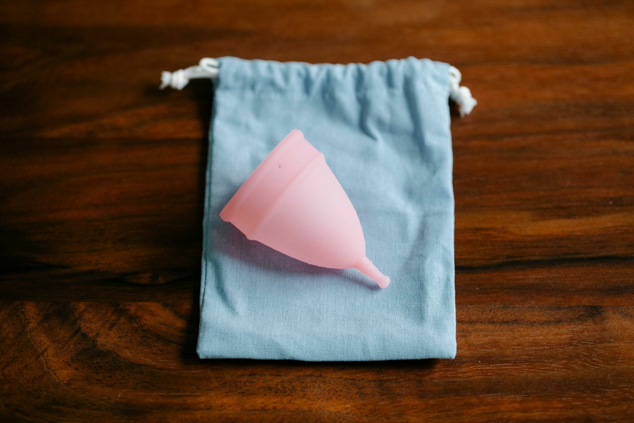 Pink menstrual cups on a light blue cotton bag