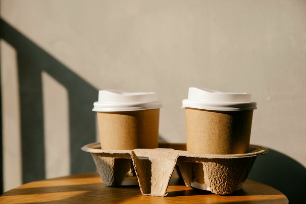 Two compostable coffee cups in a cardboard coffee cup holder.